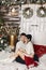 Handsome young man and beautiful model girl sit on the stairs at winter exterior of a country house with Christmas