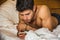 Handsome young man in bed typing on cell phone