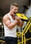 Handsome young man biting big weight disc in gym