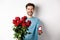 Handsome young man boyfriend making a proposal on Valentines lovers day, holding bouquet of red roses and engagement
