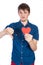 Handsome young man in denim blue shirt standing on a white background with a red paper heart in hands.