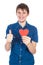 Handsome young man in denim blue shirt standing on a white background with a red paper heart in hands.