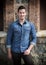 Handsome young man with denim shirt standing outdoors, smiling