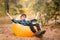 Handsome young man in hat and sunglasses lying on inflatable sofa with hands up and enjoy free time on open air