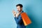 Handsome young man holding shopping bag on shoulder, turn around to look at camera and show okay gesture, recommending