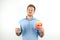 Handsome young man holds soda in papper cup and fries from fast food restaurant looks doubtful on isolated white