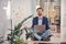 Handsome young man with laptop meditating at work