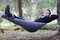 Handsome young man lies in hammock in woods