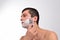 Handsome young man with lots of shaving cream on his face preparing to shave with razor