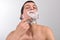 Handsome young man with lots of shaving cream on his face preparing to shave with razor