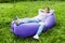 Handsome young man lying on inflatable sofa lamzac while resting on grass in park on the sun