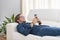 A handsome young man lying on a sofa and focused on his phone. Communication and leisure concept