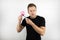 Handsome young man office worker wearing black t-shirt holding pink note paper and marker looks concentrated isolated