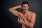 Handsome young man . Portrait of shirtless muscular man is standing on grey background and using antiperspirant. Men care