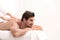 Handsome young man receiving back massage on light background. Spa salon