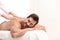 Handsome young man receiving back massage on light background. Spa salon