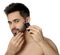 Handsome young man shaving with electric trimmer on white background