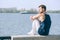 Handsome young man sitting on river quay