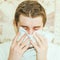 Handsome young man sneezes into a handkerchief during an epidemic.