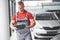 A handsome young man speaks at a car dealership, repairing a car in a workshop.