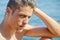 Handsome young man thinking next to the sea