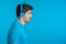 Handsome young man with trendy hairdo having fun, smiling with headphones in studio against blue background. Music