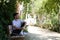 Handsome young man in white T-shirt and black trousers sitting on the wooden bench in the park waiting impatiently for someone to