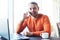 Handsome young man working with notebook, talking on the phone, smiling, looking at camera, while enjoying coffee in cafe