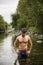 Handsome young muscle man standing in water pond, naked