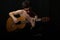 Handsome young musician playing on guitar. Naked torso. On black background