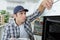 Handsome young repairman fixing oven with screwdriver