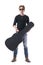 Handsome young rocker musician holding acoustic guitar black leather hard case looking at camera