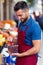 Handsome young salesman holding cherries box in health grocery shop.