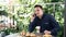 Handsome young smiling man sits in a cafe talking on phone drinking cappuccino.