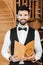 handsome young sommelier in vest and bowtie holding wine card