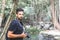 Handsome young stylish male photographer in black t-shirt and sunglasses is engaged in trekking in the green jungle