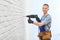 Handsome young working man using rotary hammer. Home repair