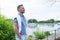 Handsome young yachtman standing on river pier. Man looking into far on his yacht. Young businessman with his yacht in marina.