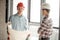 Handsomengineer in red hardhat with blueprint looking at the camera