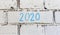 Handwriting 2020 text with blue chalk on white bricks wall