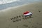 Handwriting, footprints, wave and Santa hat on the beach