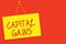 Handwriting text writing Capital Gains. Concept meaning Bonds Shares Stocks Profit Income Tax Investment Funds Yellow board wall m