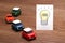 Handwritten bulb illustration and miniature cars on wood.