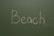 Handwritten chalk inscription beach on green board