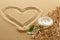 Handwritten heart on sand with lighted candles