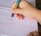 handwritten letter a, female hand holding a colored pen in the shape of a mermaid tail,in a white spiral notebook