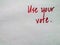 Handwritten red letters on plain background `Use your vote`