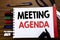 Handwritten text showing Meeting Agenda. Business concept for Business Schedule Plan Written on notebook, wooden background with o