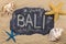 Handwritten word BALI written in chalk, among seashells and starfishes