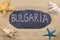 Handwritten word BULGARIA written in chalk, among seashells and starfishes